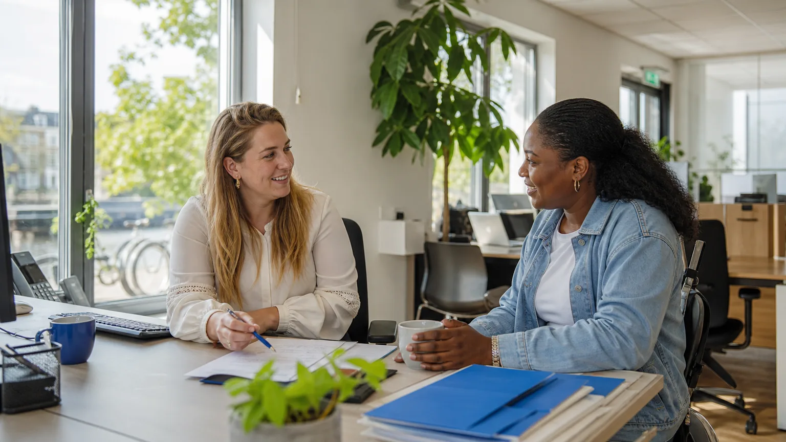 Staffing coordinator and temporary worker having a relaxed conversation in a bright branch office